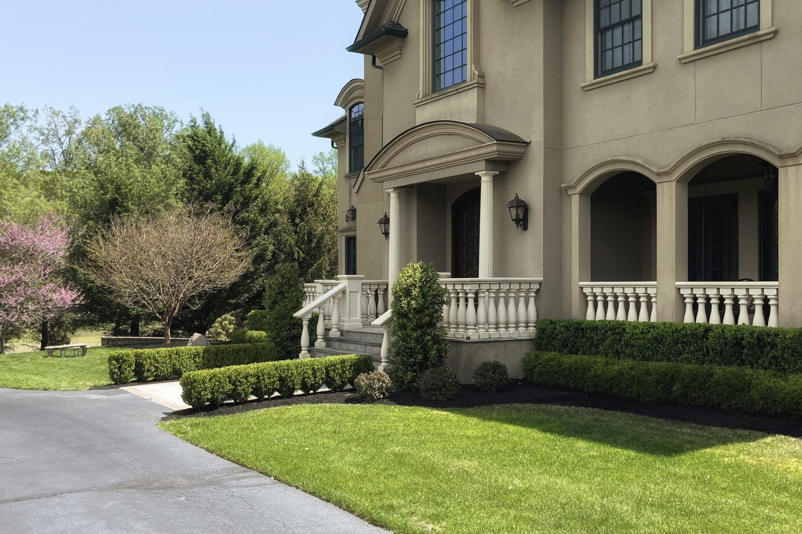Front entrance landscaping with planted garden beds and neatly maintained lawn.