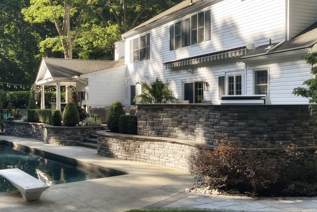 Newly installed backyard stone patio with curved structure and garden beds
