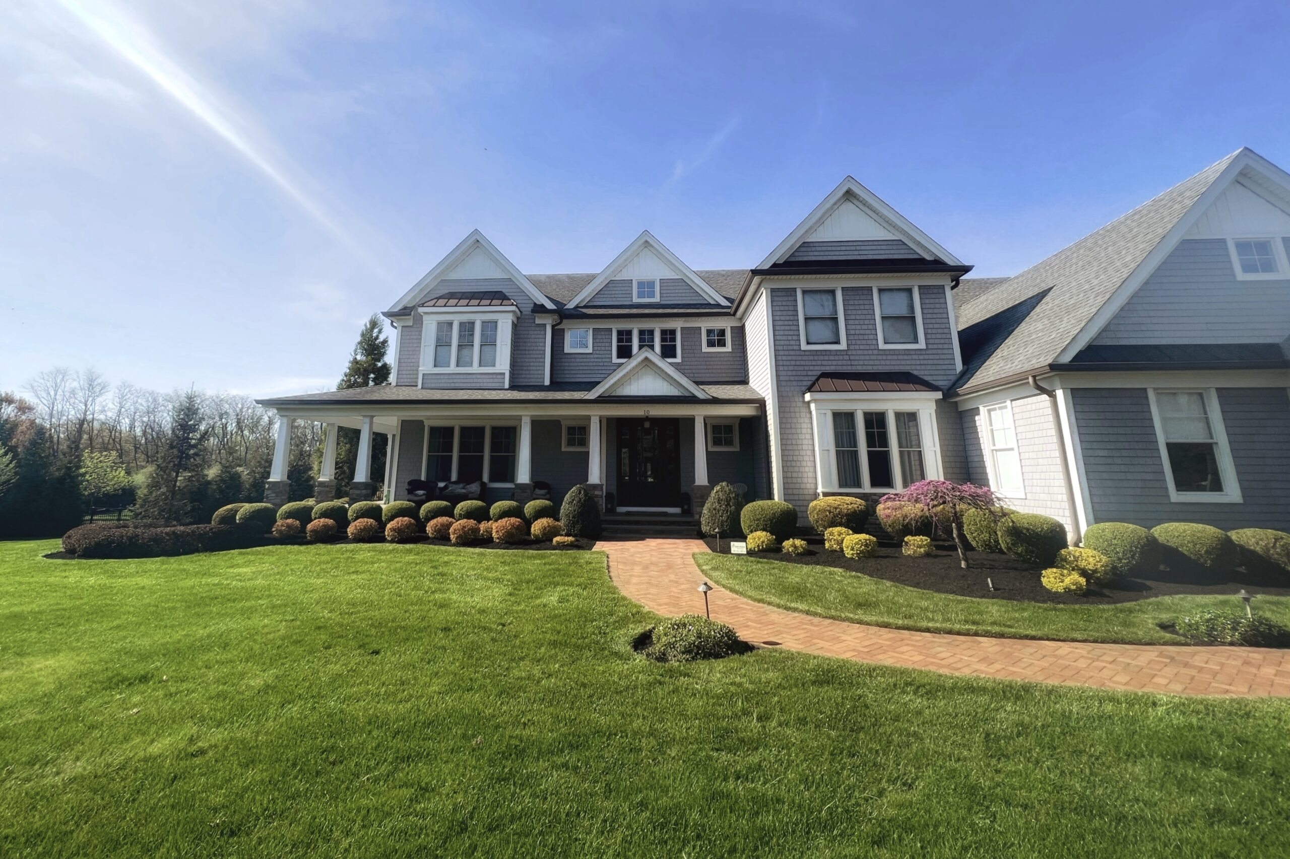 Wide shot front yard landscape design with layered shrubs and planting beds in Monmouth County, NJ