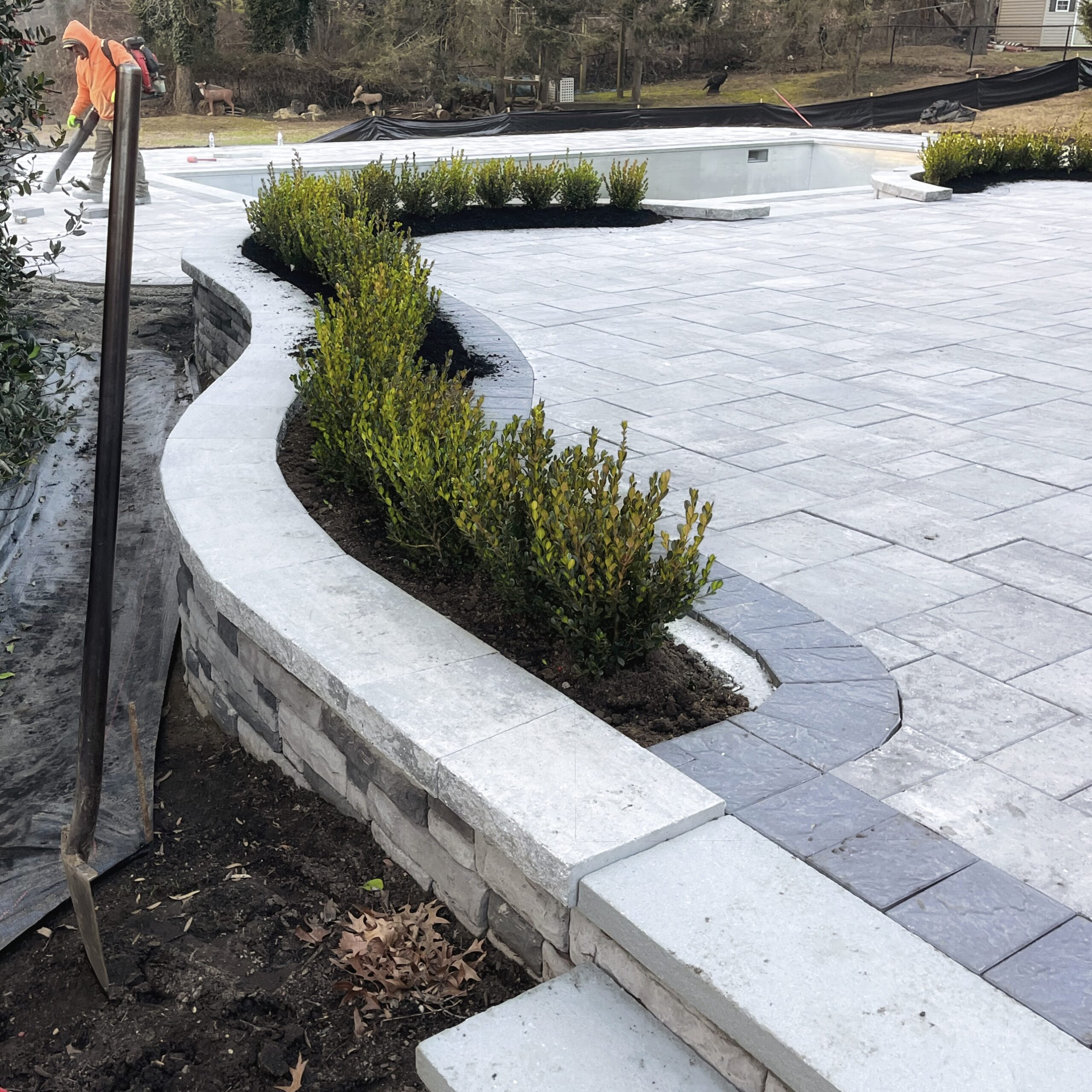 Stone pool patio installation with clean hardscape and landscaping
